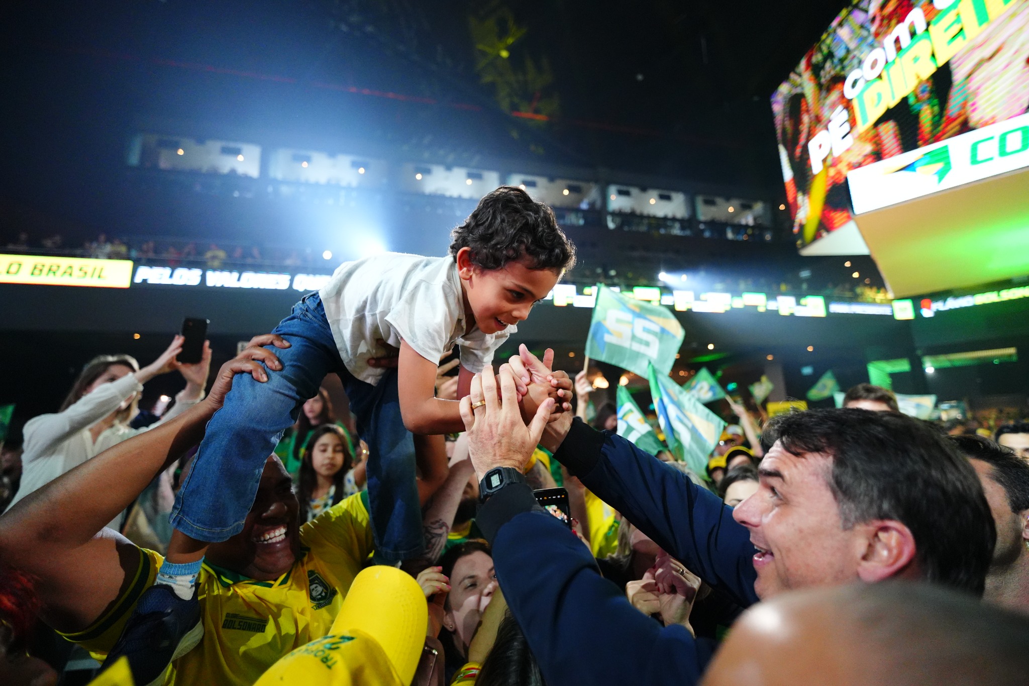Flávio Bolsonaro cumprimentando criança durante evento público